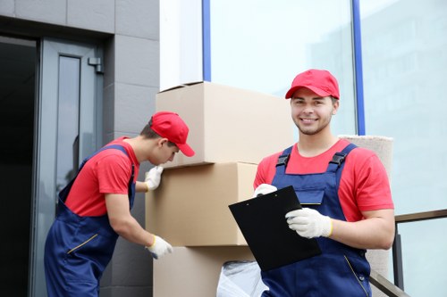 Movers carrying household items through a residential street in Yeading